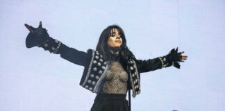 A female singer performing on stage with arms outstretched
