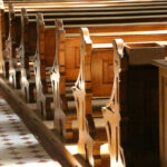 Interior of a church featuring wooden pews and natural light streaming in