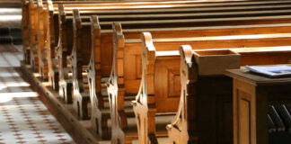 Interior of a church featuring wooden pews and natural light streaming in