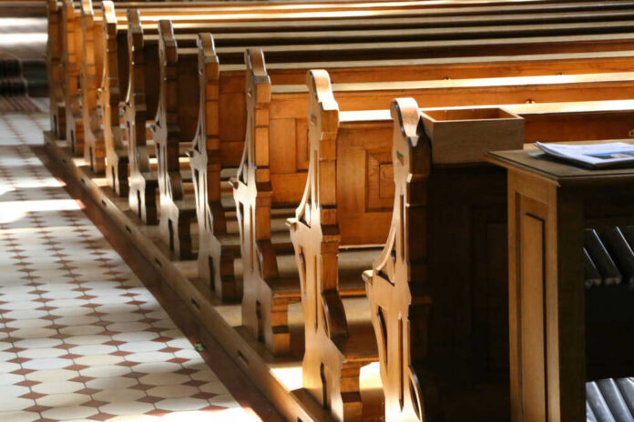 Interior of a church featuring wooden pews and natural light streaming in