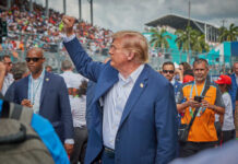 A political figure raising a fist in a crowd at a sports event