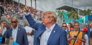 A political figure raising a fist in a crowd at a sports event