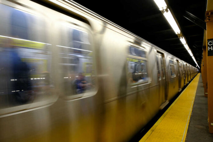 A subway train in motion at a station with a yellow platform