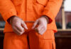 A person in an orange jumpsuit with handcuffs