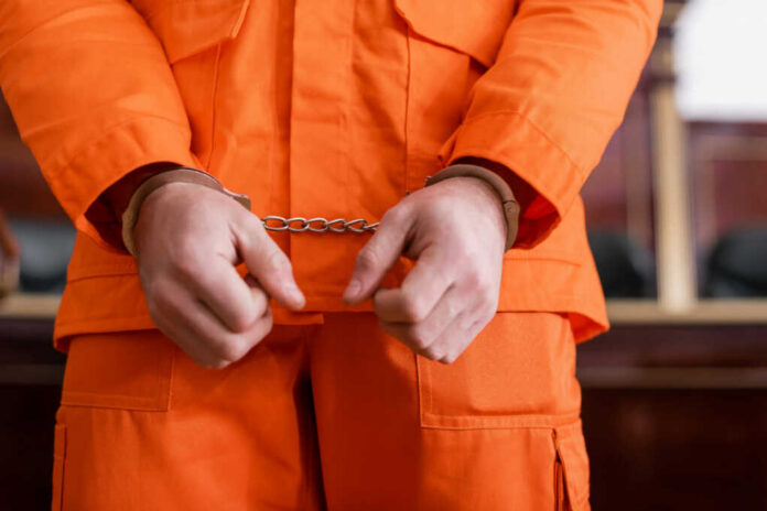 A person in an orange jumpsuit with handcuffs