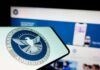 Close-up of a mobile device displaying the TSA logo with a blurred background of a website