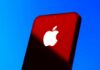 Close-up of a smartphone with the Apple logo against a red and blue background