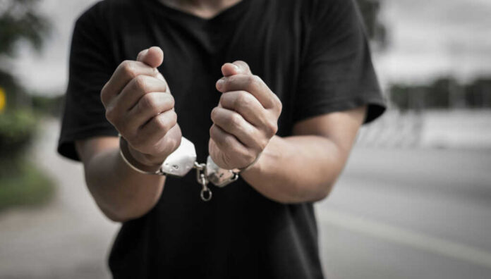 Close-up of hands in handcuffs against an outdoor background