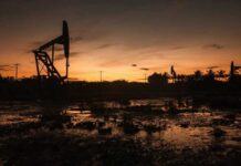 Silhouette of oil pumps against a sunset sky