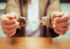 Close-up of hands holding handcuffs in a serious context