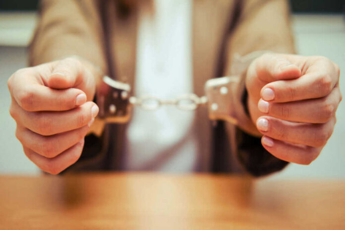 Close-up of hands holding handcuffs in a serious context