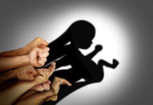 A collection of hands creating a shadow silhouette of a fetus