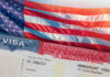 Close-up of a US visa with an American flag in the background