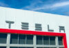 Tesla logo on a modern building with a blue sky