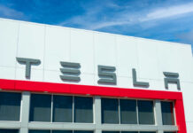 Tesla logo on a modern building with a blue sky