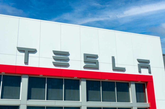 Tesla logo on a modern building with a blue sky