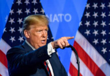 A man delivering a speech with American flags in the background