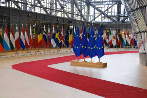 Flags of European countries displayed in a modern hall with a red carpet