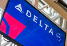 Delta’s SHOCKING Profit Surge Amid Global Chaos Delta Airlines logo displayed on an airport screen