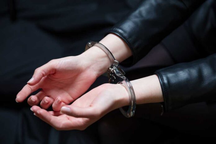 Close-up of hands in handcuffs wearing a leather jacket