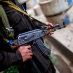 Soldier holding an AK-47 rifle in a conflict area