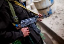Soldier holding an AK-47 rifle in a conflict area