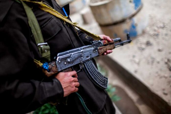 Soldier holding an AK-47 rifle in a conflict area