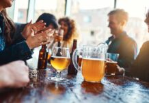 Group of friends enjoying drinks at a bar with a pitcher of beer on the table