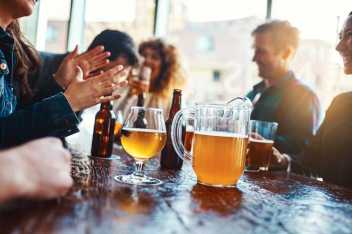 Group of friends enjoying drinks at a bar with a pitcher of beer on the table