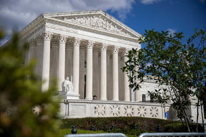 The Supreme Court building with columns and a statue in front