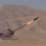 A missile launching into the sky with smoke and flames in a desert setting