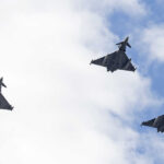 Three fighter jets flying in formation against a cloudy sky