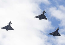 Three fighter jets flying in formation against a cloudy sky