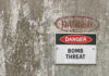 Iran War Echoes: Blast Shakes Dutch Christian Center Warning sign indicating a bomb threat on a weathered wall