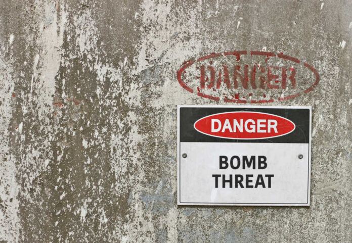 Warning sign indicating a bomb threat on a weathered wall