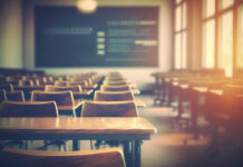 Empty classroom with wooden desks and chairs, illuminated by natural light