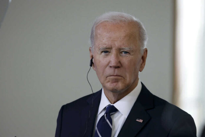 A serious-looking man in a suit with an earpiece, standing indoors
