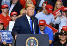 Celebrity Hype Warps Voter Reality A speaker at a political rally smiling in front of an enthusiastic crowd wearing red hats