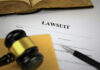 Outrage Erupts: Student Suicide and Harsh Law Clash A gavel resting on a legal document titled 'LAWSUIT' with a pen and an open book in the background