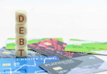 Stack of wooden blocks spelling DEBT on top of various credit cards