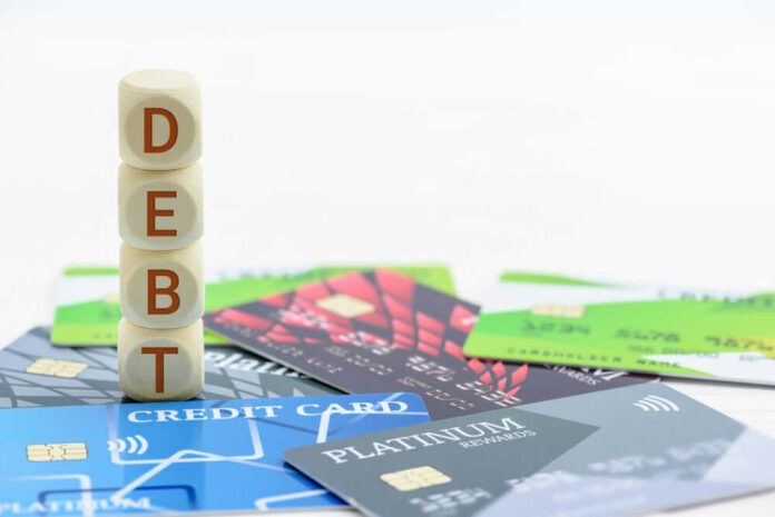 Stack of wooden blocks spelling DEBT on top of various credit cards