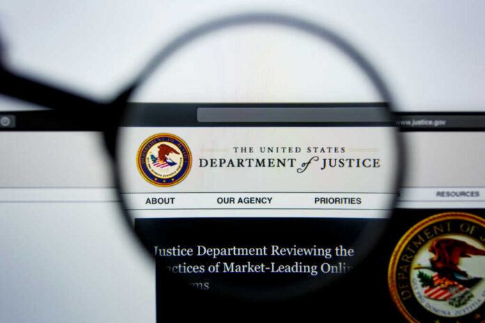 shutterstock_1466142779-1 Close-up view of the Department of Justice website through a magnifying glass