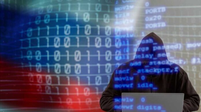 A hooded figure working on a laptop with binary code in the background