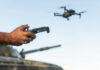 SOCOM’s Wild AI Experiment: Testing Gaps Exposed Person controlling a drone with a remote while a tank is in the background