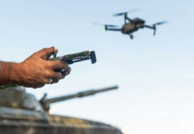 SOCOM’s Wild AI Experiment: Testing Gaps Exposed Person controlling a drone with a remote while a tank is in the background