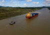 Shocking Probe: China’s Shipping Conspiracy Unveiled A cargo ship being assisted by a tugboat in a canal