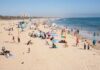 Inflation Nightmare: Beach Chair Prices Skyrocket Crowded beach with people sunbathing and playing in the water