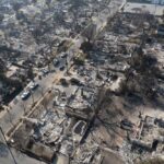 Aerial view of a neighborhood devastated by wildfire, showing burned structures and debris