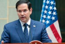 Marco Rubio speaking at a podium with an American flag in the background