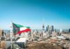 Kuwait flag waving over a city skyline with modern buildings